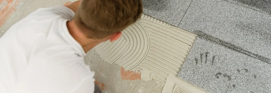 Person verlegt Fliesenkleber auf dem Boden